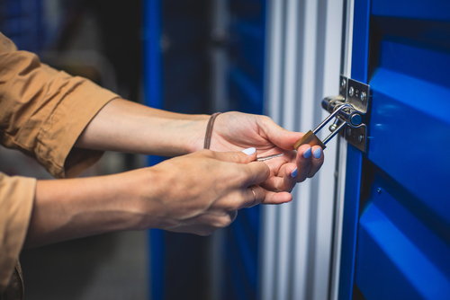 A man closing his bleu doors storage unit with a lock